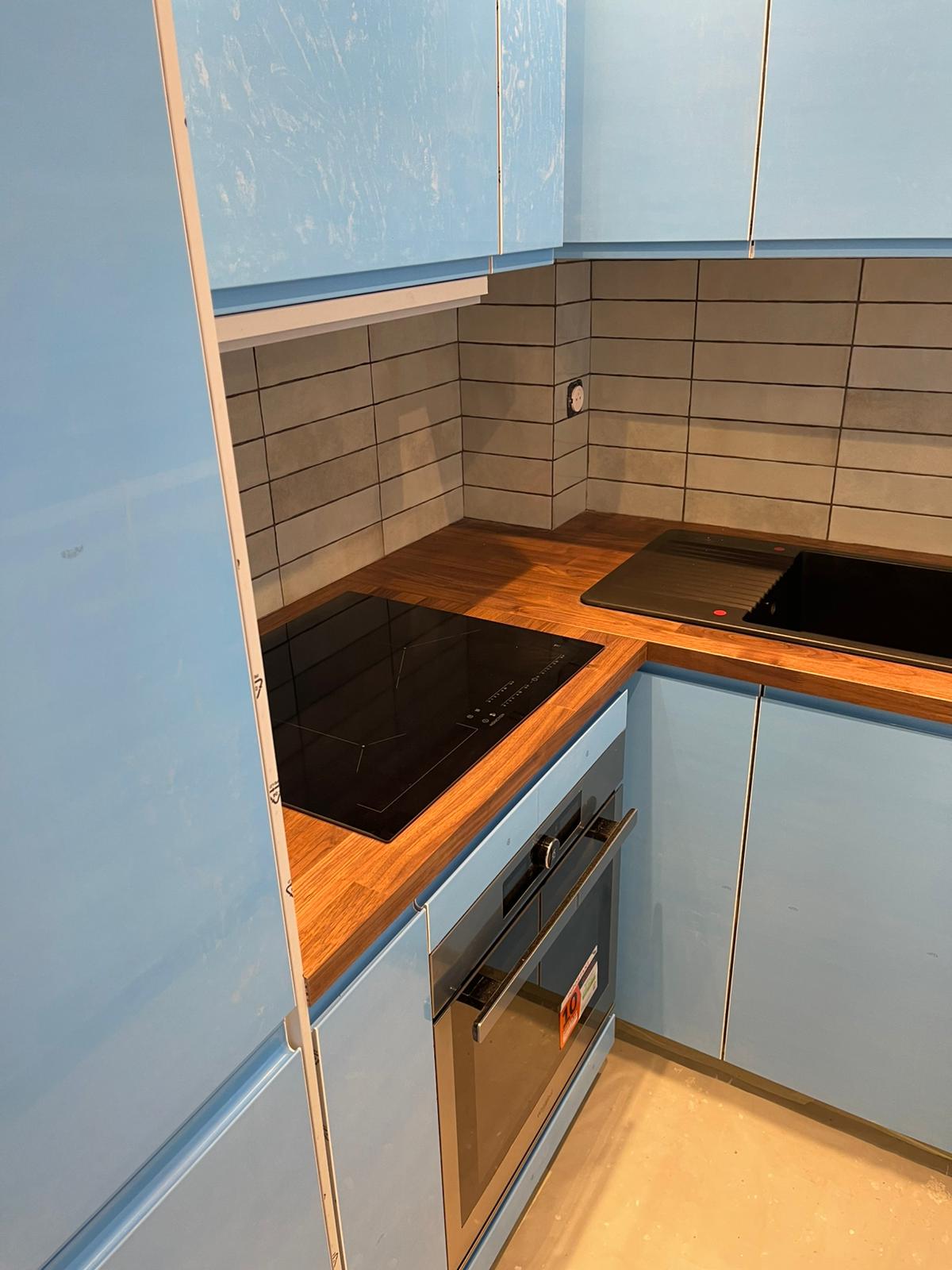 Cuisine compacte bleue avec induction et crédence métro grise